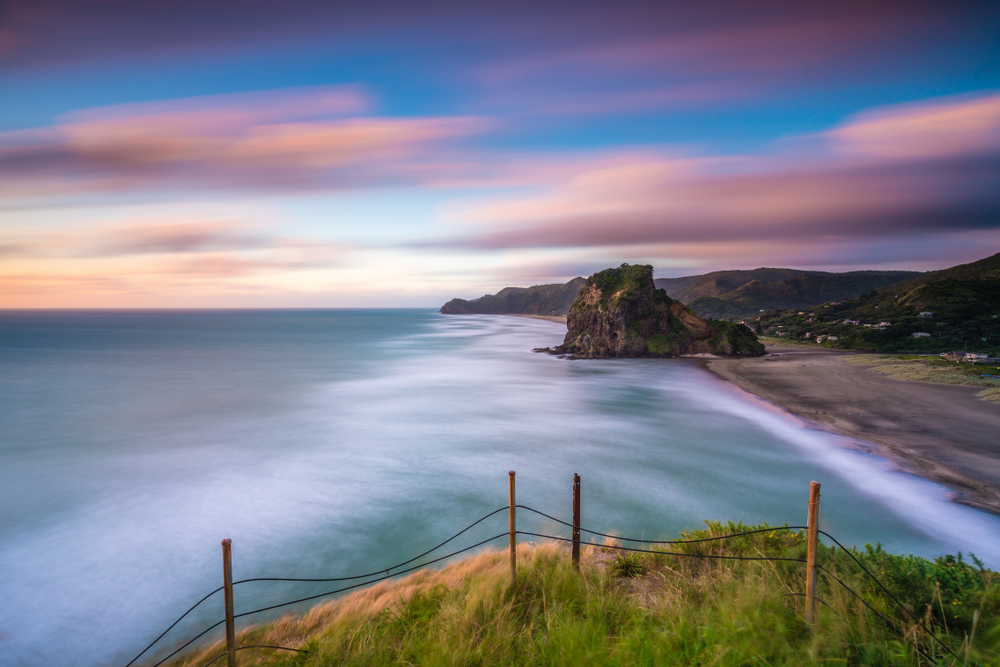 Colourful sky, and emerald sea, with a long distance view up the coast of Piha and lion rock.