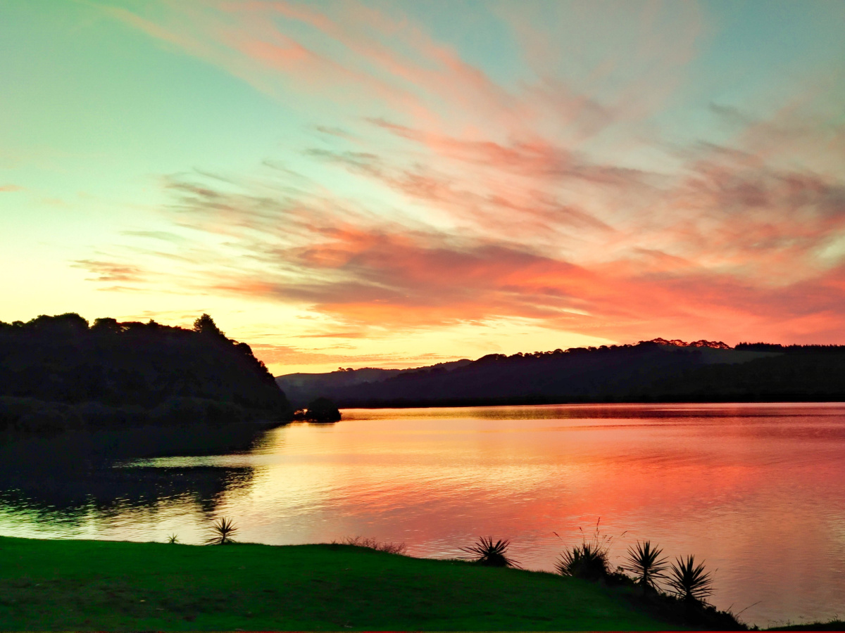 Perfect pastel colours dance in the sky as the sun begins to rise of Waitangi, NZ.